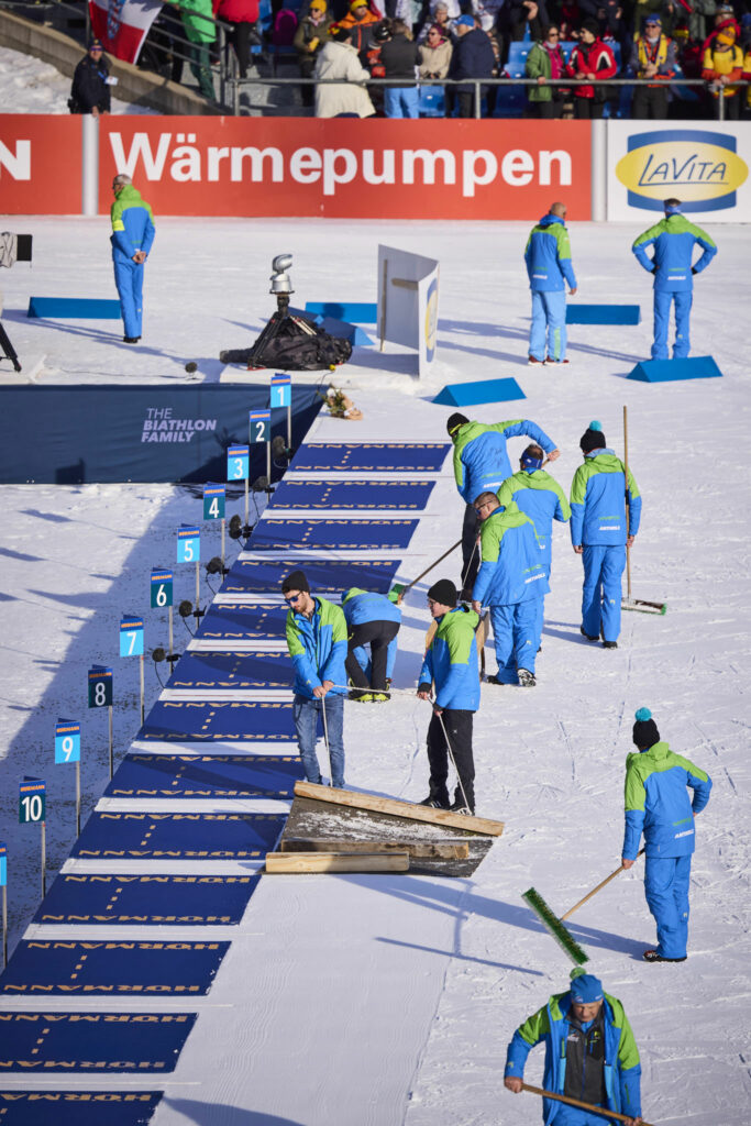 Freiwillige Helfer präparieren den Schnee in der Olympic Arena in Antholz